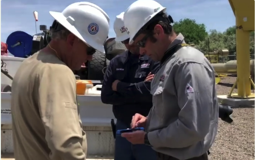 Two DCP Midstream field operators and Joel (right) in hard hats, testing a mobile app on site